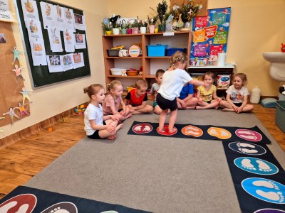 Dzieći skaczące po kolorowych planszach rozłożonych na podłodze w klasie