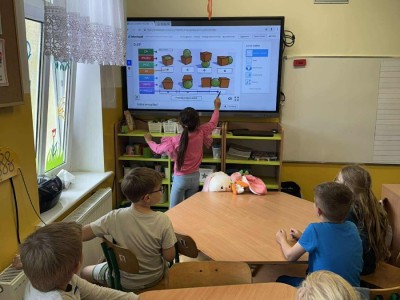 Dzieci rozwiązują zadania na multimedialnej tablicy